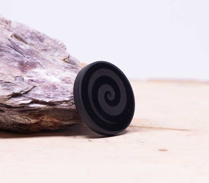 Black authentic carbon-rich Shungite tab with a geometric swirl pattern used for a mindful tech routine.