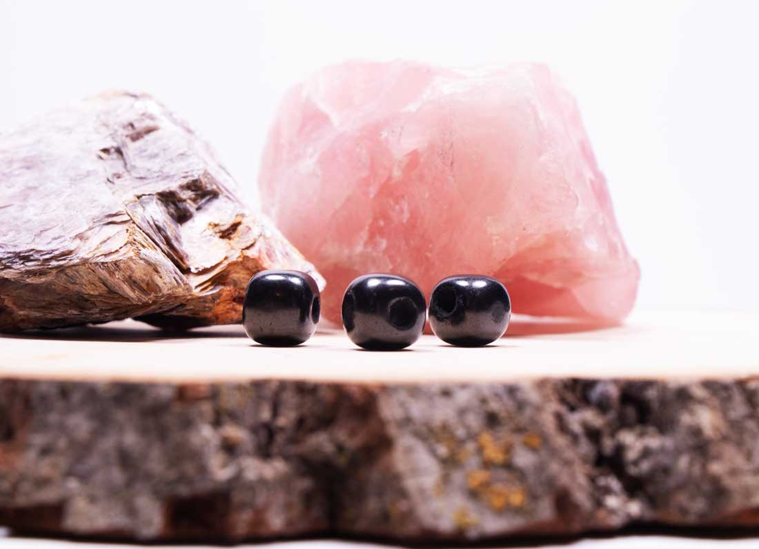 • Side view of three polished black Shungite cube beads standing in a line, showcasing their smooth rounded edges and natural mineral gloss.