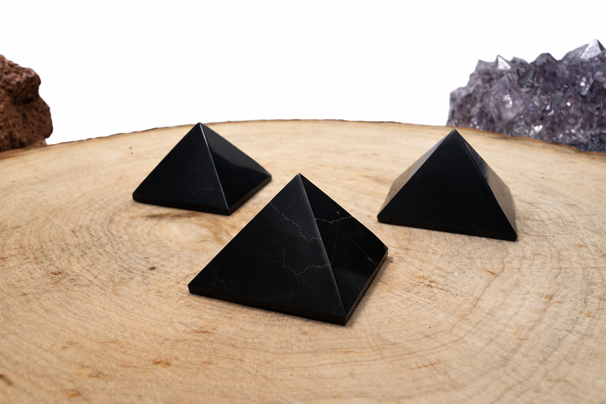 A bundle of three mini carbon-rich Shungite pyramids for tech workspace placement, showcasing a smooth polished finish.