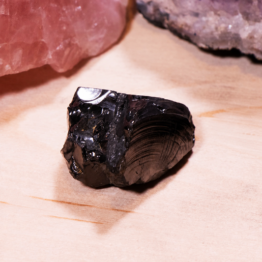 Medium-sized authentic Elite Noble Shungite stone with a shiny silver-black metallic finish on a wooden surface.