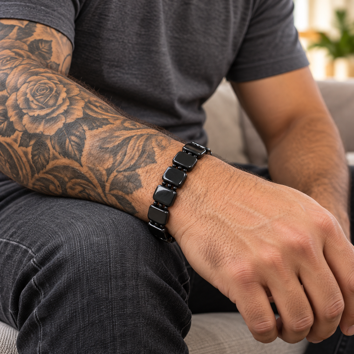 Lifestyle view of a man with a detailed arm sleeve tattoo wearing a black Shungite grounding bracelet on a broad wrist.