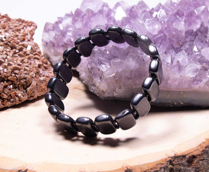 Upright angled view of an authentic men's Shungite grounding bracelet showcasing the smooth, polished inner and outer surfaces of the flat rectangular beads against an amethyst background