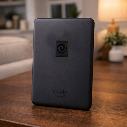 A black portable electronic reading tablet resting on a polished wood surface in a cozy living room setting.