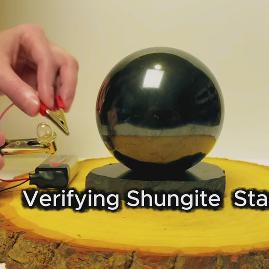 Testing the electrical conductivity of a black shungite sphere and display stand.