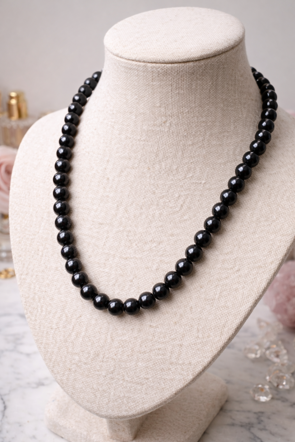 An elegant Midnight Royale black polished Shungite beaded necklace displayed on a beige fabric bust mannequin.