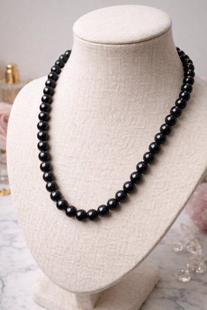 An elegant Midnight Royale black polished Shungite beaded necklace displayed on a beige fabric bust mannequin.