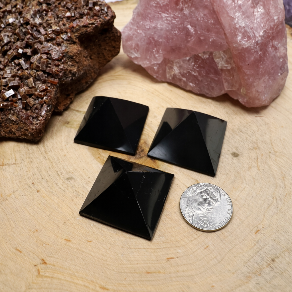 A bundle of three mini carbon-rich Shungite pyramids for tech workspace placement, showcasing a smooth polished finish.